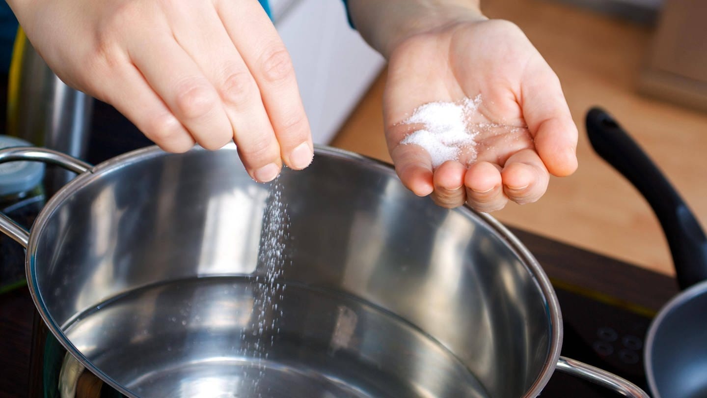 Eine Frau gibt Salz in einen Topf mit Wasser: Kocht gesalzenes Wasser schneller? (Foto: IMAGO, IMAGO / Panthermedia)