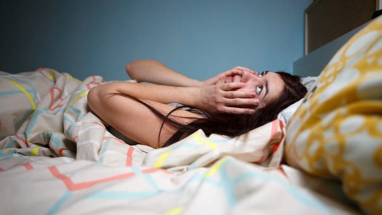 Eine junge Frau liegt wach im Bett: Wer abends zu spät isst, kann Probleme mit dem Einschlafen und Durchschlafen bekommen. Der Magen hat dann noch zu viel zu arbeiten. (Foto: Colourbox)