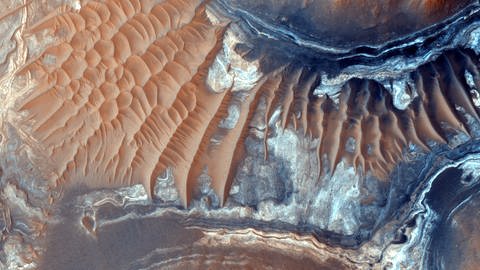 Bild des Bodens einer 600 Meilen langen Schlucht namens Ius Chasma, die Teil der Valles Marineris ist, dem größten bekannten Schluchtsystem im Sonnensystem. Das dunkle Gestein ist ein alter Lavastrom und die helleren Bereiche sind Mega-Wellen. Aufnahme: Kamera des High Resolution Imaging Science Experiment (HI RISE) des Mars Reconnaissance Orbiter. (Foto: IMAGO, IMAGO / United Archives International)