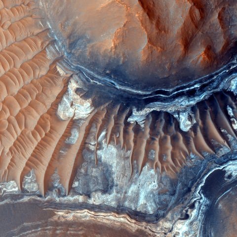 Bild des Bodens einer 600 Meilen langen Schlucht namens Ius Chasma, die Teil der Valles Marineris ist, dem größten bekannten Schluchtsystem im Sonnensystem. Das dunkle Gestein ist ein alter Lavastrom und die helleren Bereiche sind Mega-Wellen. Aufnahme: Kamera des High Resolution Imaging Science Experiment (HI RISE) des Mars Reconnaissance Orbiter. (Foto: IMAGO, IMAGO / United Archives International)