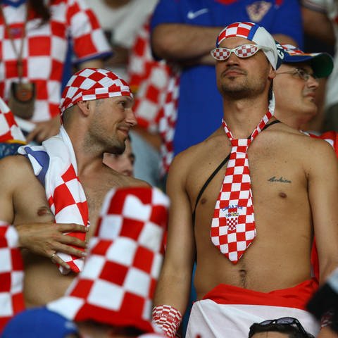 Kroatischer Fußballfan hat seinen Oberkörper nur durch eine Krawatte in den Landesfarben bedeckt: Die "Kroaten" – die sich selbst "Hrvati" nennen – sind zum Namensgeber des Tuches geworden, das wir heute als "Krawatte" kennen (Foto: IMAGO, IMAGO / ActionPictures)