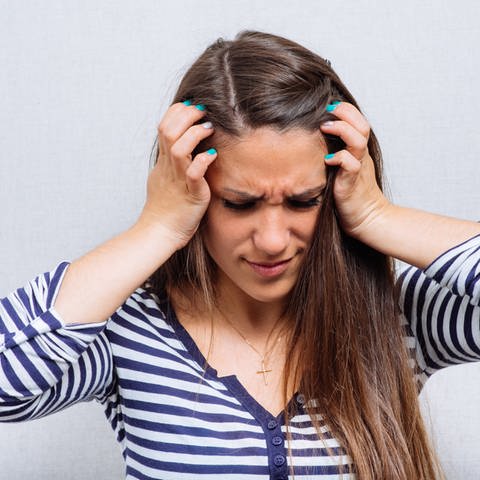 Eine Frau hält sich mit schmerzverzerrtem Gesicht die Ohren zu: Migräne ist eine ernste Erkrankung. Man muss sie intensiv behandeln, um Komplikationen wie Tinnitus möglichst zu vermeiden. (Foto: Colourbox)