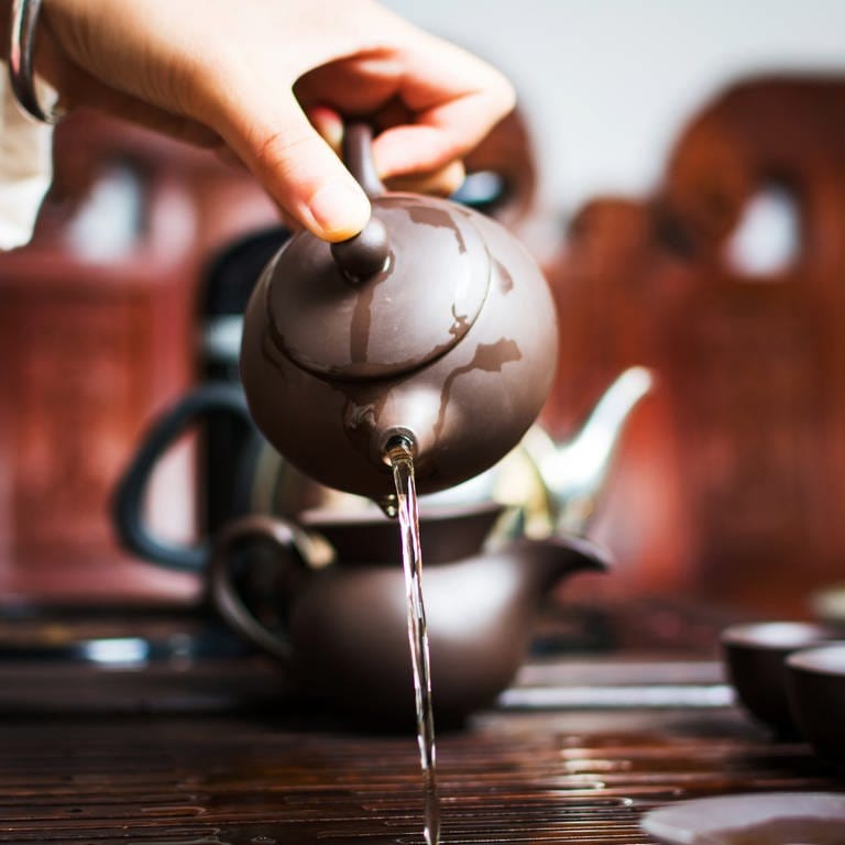 Eine Frau schenkt während einer chinesischen Teezeremonie den ersten Aufguss aus: Ein oft gehörter Ratschlag lautet: Schwarzen Tee solle man mit kochendem Wasser übergießen, bei grünem Tee dagegen soll das Wasser nicht heißer sein als 60 bis 80 Grad. Doch die Meinungen darüber gehen auseinander. (Foto: IMAGO, IMAGO / agefotostock)