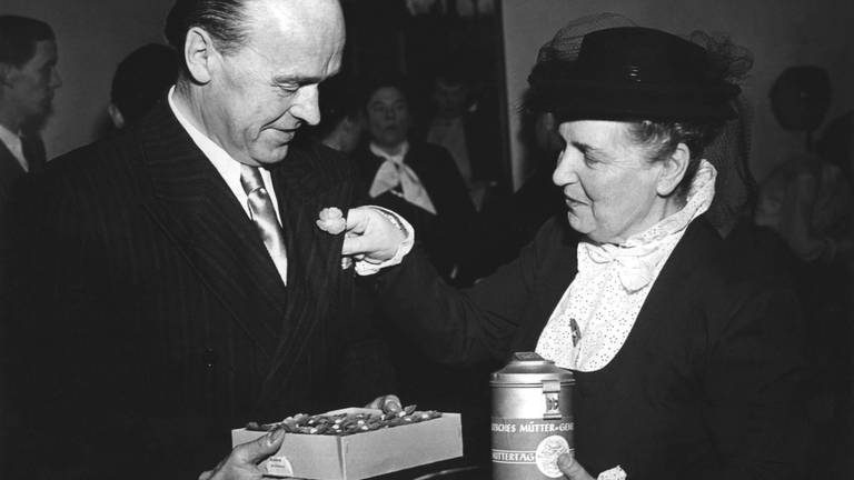 Elly Heuss-Knapp sammelt im März 1950 für den Muttertag und steckt einem Journalisten eine Blume ins Knopfloch. Die Frau des Bundespräsidenten hatte am 31. Januar 1950 in Bonn die Gründung des Mütter-Genesungswerkes bekanntgegeben. (Foto: picture-alliance / Reportdienste, picture-alliance / dpa | dpa)