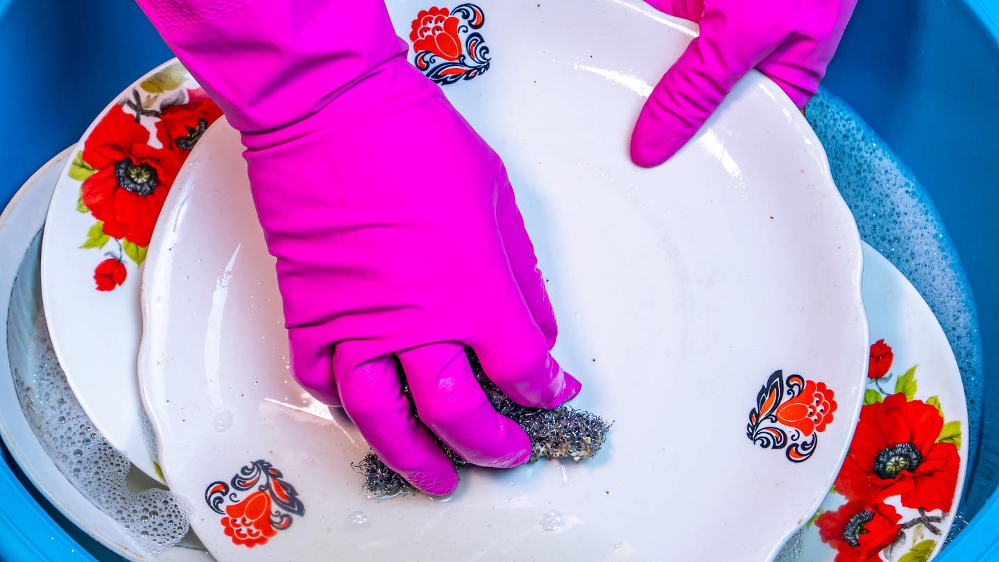 Hände in pinkfarbenen Handschuhen spülen einen Teller: Beim Spülen sollte man darauf achten, die Lappen regelmäßig zu wechseln. Spültücher mit eingewebten Silverfäden bringen keinen zusätzlichen Nutzen in Bezug auf die Hygiene. (Foto: picture-alliance / Reportdienste, picture alliance / PantherMedia | -)