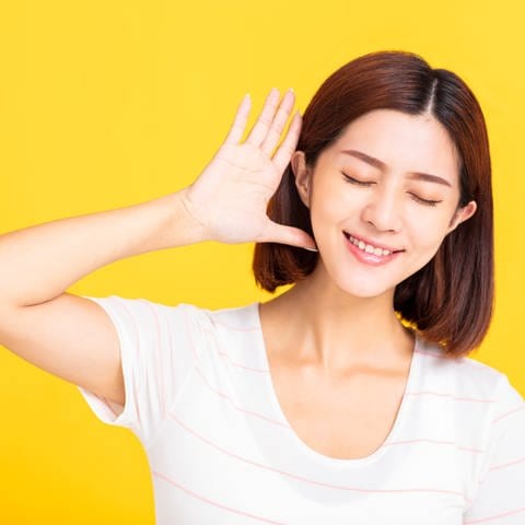 Junge Frau hält sich lauschend eine Hand hinter das Ohr: Absolutes Gehör bedeutet, dass ich zu jemandem sagen kann "Sing mal ein G!" – und die Person trifft dann genau den richtigen Ton. Das ist eine besondere musikalische Gabe.  (Foto: IMAGO, IMAGO / Panthermedia)