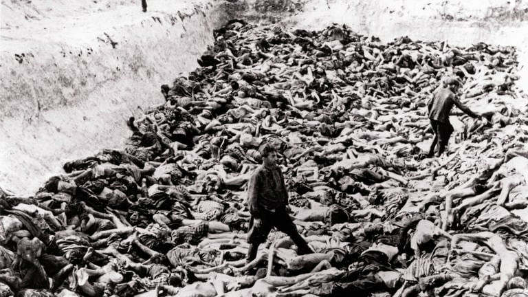 KZ Bergen-Belsen. Ein Massengrab, das nach der Übernahme des Lagers durch britische Truppen gegraben wurde. Im Lager wurden 55.000 Häftlinge, viele mit Typhus und Ruhr, gefunden. Tausende starben nach der Befreiung. Das restliche SS-Personal und die Wachen wurden von bewaffneten alliierten Truppen gezwungen, die Leichen in einer Grube von der Größe eines Tennisplatzes zu begraben (15. April 1945)