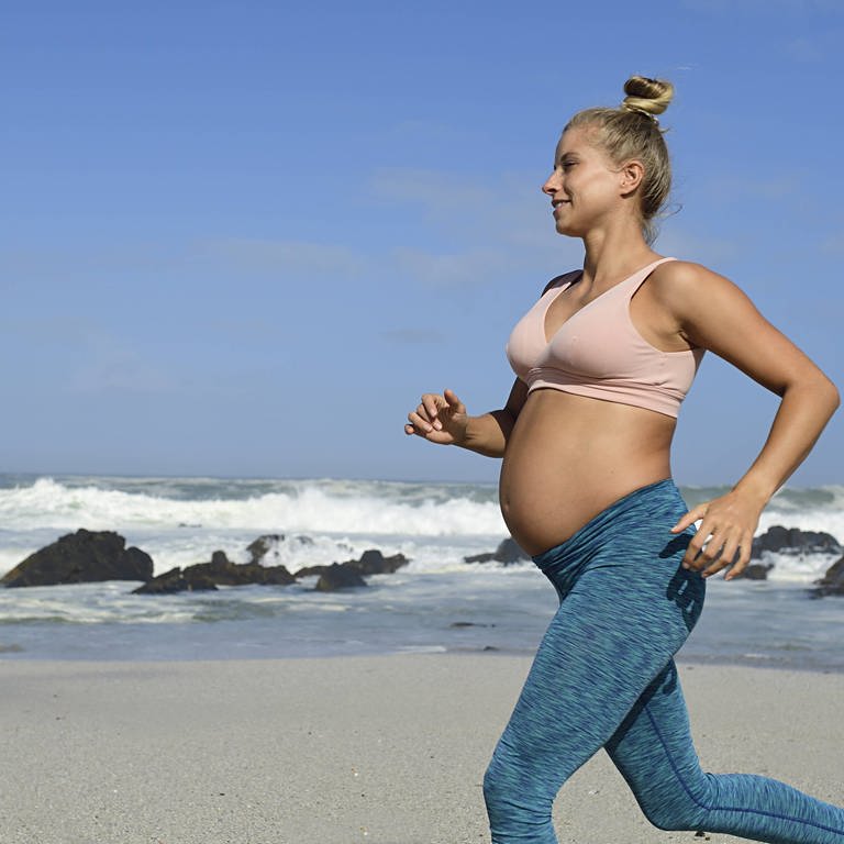 Schwangere treibt Sport am Strand