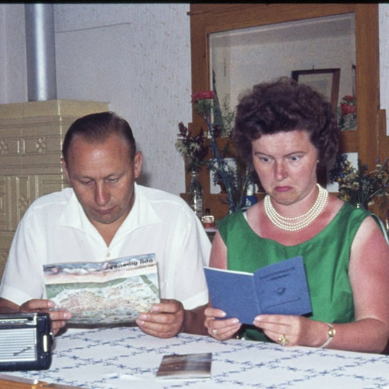 Ehepaar bei der Urlaubsplanung um 1970: Das Postsparbuch gehört auch dazu
