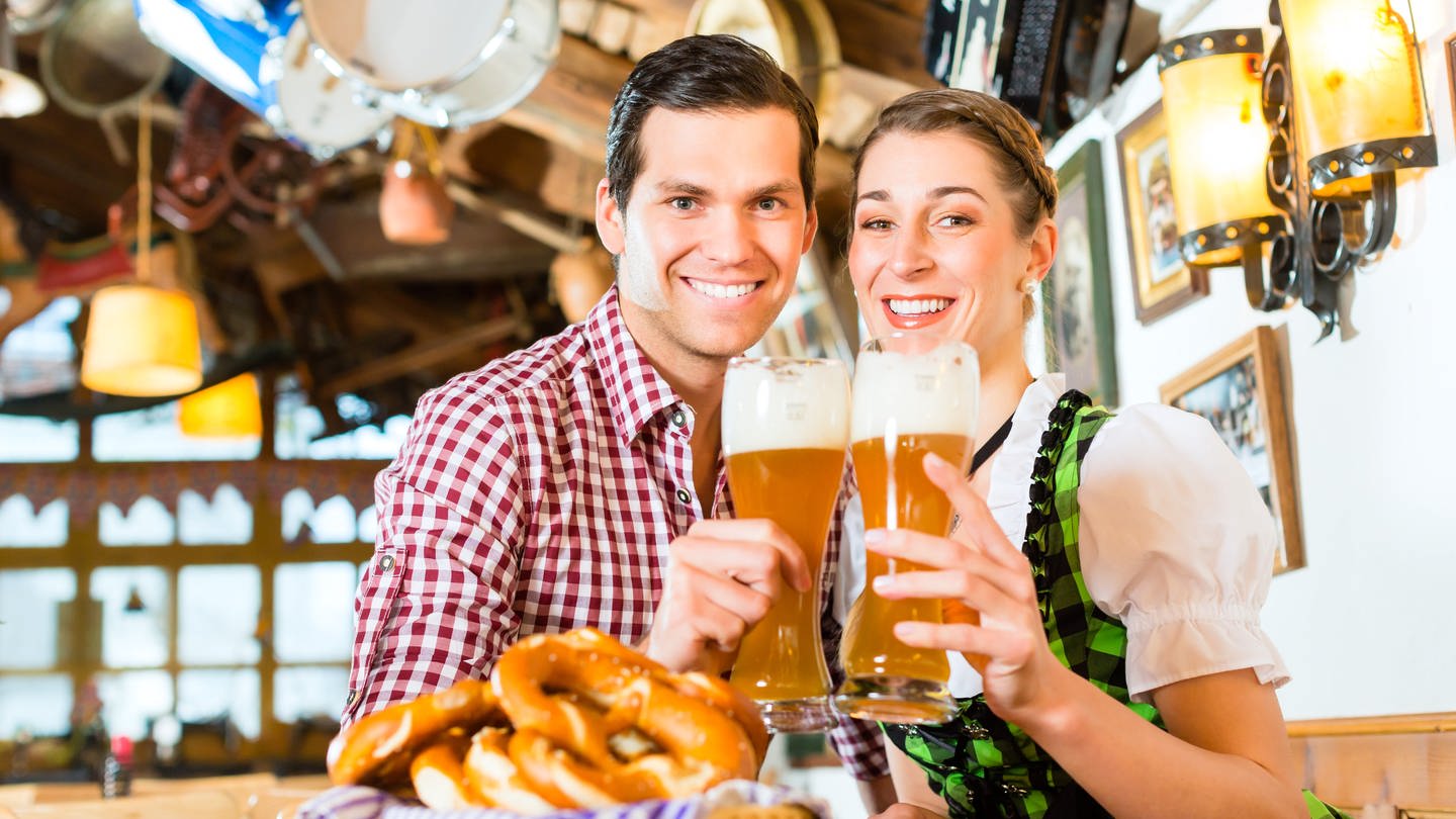 Mann und Frau in Tracht mit je einem Bierglas in der Hand: Deutsche Männer trinken mehr als sechsmal so viel Bier wie die Frauen. Die Gründe sind unklar. Zum einen trinken Männer grundsätzlich mehr Alkohol. Aber beim Bier sind die Unterschiede besonders auffallend. (Foto: Colourbox)