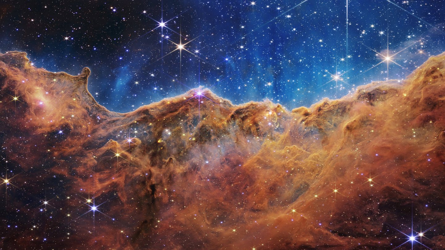 Diese Landschaft aus Bergen und Tälern, die mit glitzernden Sternen übersät ist, ist eigentlich der Rand einer nahe gelegenen, jungen Sternentstehungsregion namens NGC 3324 im Carina-Nebel. Das Bild wurde vom neuen James-Webb-Weltraumteleskop der NASA im Infrarotlicht aufgenommen. (Foto: IMAGO, IMAGO / ZUMA Wire)