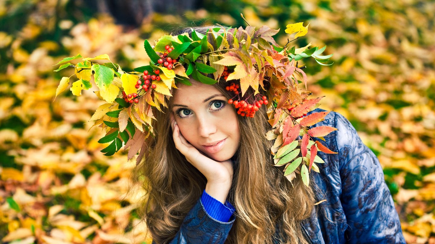 Junge Frau mit Herbstlaub auf dem Kopf: Im Spätsommer und Herbst gehen überdurchschnittlich viele Haarfollikel in eine Ruhephase über und wir verlieren mehr Haare als sonst. (Foto: IMAGO, IMAGO / Pond5 Images)