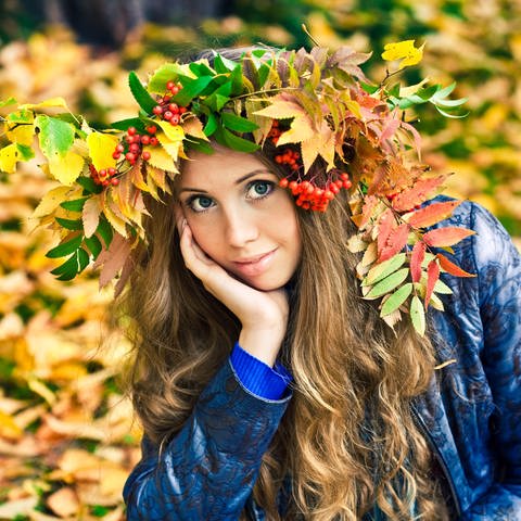Junge Frau mit Herbstlaub auf dem Kopf: Im Spätsommer und Herbst gehen überdurchschnittlich viele Haarfollikel in eine Ruhephase über und wir verlieren mehr Haare als sonst. (Foto: IMAGO, IMAGO / Pond5 Images)