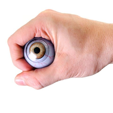Eine Faust hält ein künstliches Auge: "Das passt wie die Faust aufs Auge" – ist das positiv oder negativ zu verstehen? (Foto: IMAGO, IMAGO / Panthermedia)