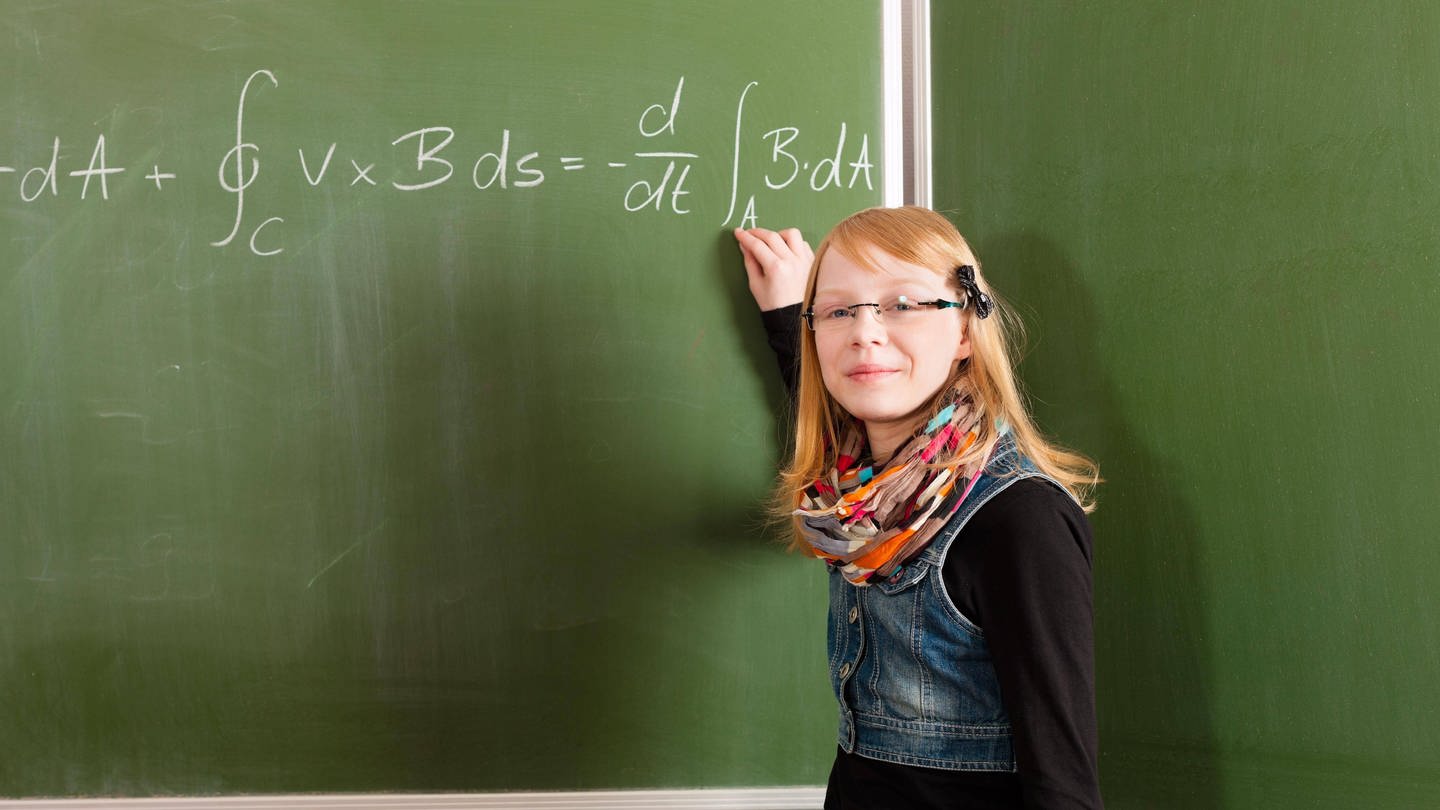 Schülerin steht vor Tafel mit Formel (Foto: IMAGO, imago images / Panthermedia)
