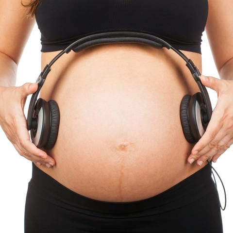 Kopfhörer auf dem Bauch einer Schwangeren