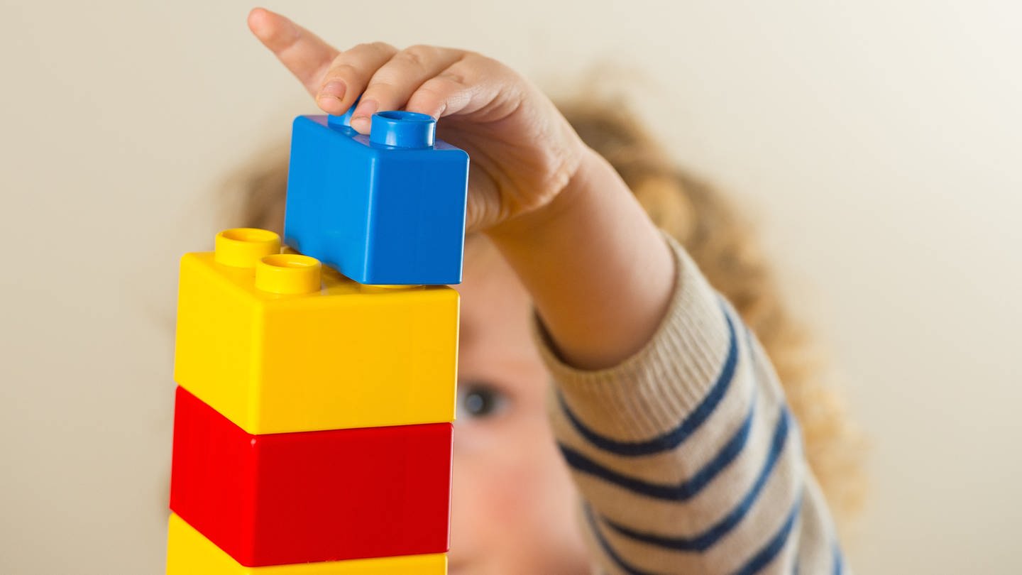 Kleinkind baut Turm mit Legosteinen