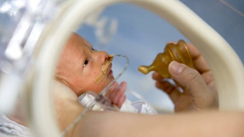 Ein Frühgeborenes bekommt tropfenweise Muttermilch durch einen Sauger angeboten. So soll der natürliche Saugreflex des Kindes geweckt werden. (Foto: IMAGO, imago images / epd)