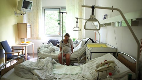 Pregnant woman with pain sits alone on a hospital bed (Photo: IMAGO, imago stock&people)
