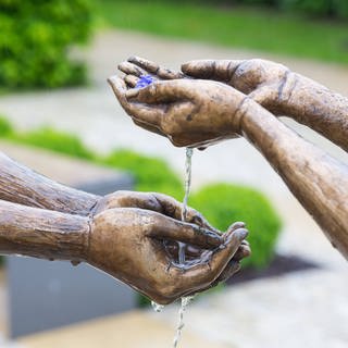 Hände zweier Bronzefiguren, die sich das Wasser reichen, in Radebeul, Sachsen (Foto: imago images, Gabriele Hanke via www.imago-images.de)