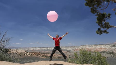 Mann springt in die Luft mit großem Ballon (Foto: imago images, imago stock&people)