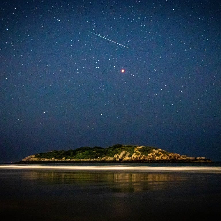 Meteor und Sternenhimmel über einer Insel (Foto: IMAGO, Cavan Images via www.imago-images.de)