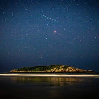 Meteor und Sternenhimmel über einer Insel (Foto: imago images, Cavan Images via www.imago-images.de)