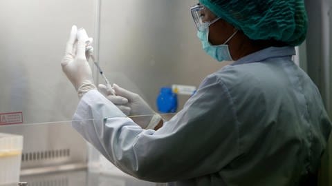 Eine Wissenschaftlerin im Labor extrahiert mit einer Spritze einen Impfstoff (Foto: IMAGO, Imago Images / Zuma Wire)
