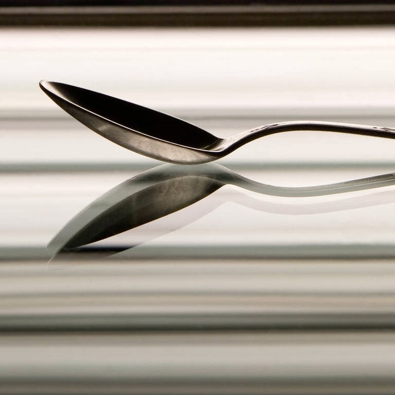 Ein Silberlöffel reflektiert in einem Spiegel (Foto: IMAGO, Dmitry Pistrov 2007 via www.imago-images.de)