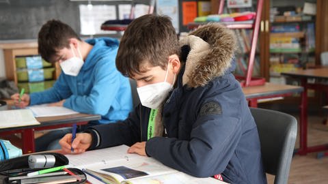 Zwei Schüler mit dicken Jacken im Unterricht (Foto: IMAGO, IMAGO / Eibner)