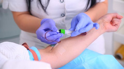 Pflegerin nimmt einer Person Blut ab (Foto: imago images, agefotostock)