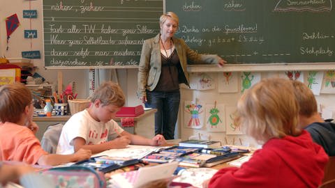 Eine Lehrerin unterrichtet eine Klasse. (Foto: imago images, Imago / Sven Simon)