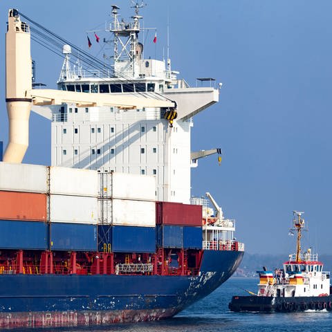 Containerschiff neben kleinem Schlepper: Warum befindet sich die Kommandobrücke bei Schiffen mal hinten, mal vorne, mal in der Mitte? (Foto: IMAGO, IMAGO / Shotshop)