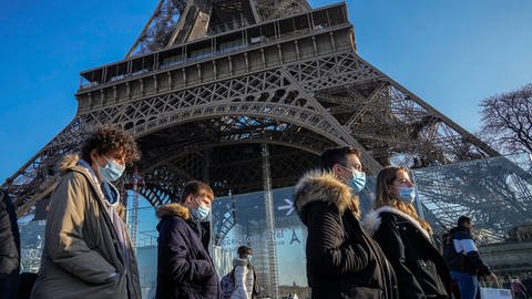 Menschen tragen Schutzmasken und gehen am Eiffelturm vorbei. (Foto: picture-alliance / Reportdienste, picture alliance/dpa/AP)