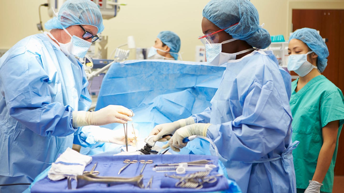Ein Chirurg und eine Chirurgin stehen im OP und operieren einen Patienten (Foto: IMAGO, IMAGO / Shotshop)