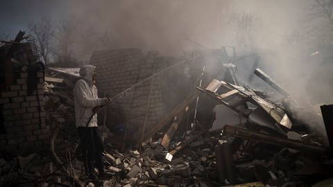 Nachbarn versuchen das Feuer eines Hauses zu löschen, das nach einem russischen Angriff in Charkiw zerstört wurde. (Foto: picture-alliance / Reportdienste, picture alliance/dpa/AP)