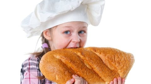 Kleine Bäckerin beißt in Brot