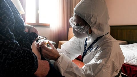 Arzt in Vollschutz injiziert Heparin (Foto: IMAGO, IMAGO / ZUMA Wire)
