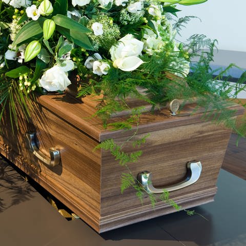 Sarg mit Blumen: Warum bestatten wir unsere Toten in Särgen? (Foto: IMAGO, IMAGO / agefotostock)