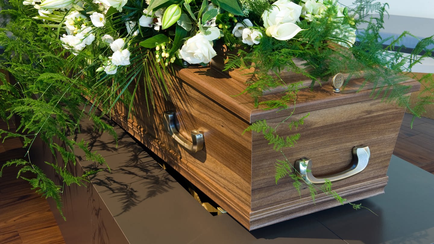 Sarg mit Blumen: Warum bestatten wir unsere Toten in Särgen? (Foto: IMAGO, IMAGO / agefotostock)