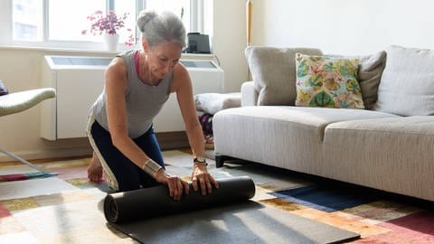 Ältere Dame mit einer Yogamatte (Foto: IMAGO, IMAGO / Cavan Images)