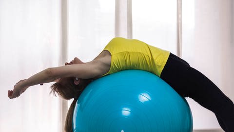 Übung auf einem Pilatesball (Foto: IMAGO, IMAGO / Addictive Stock)
