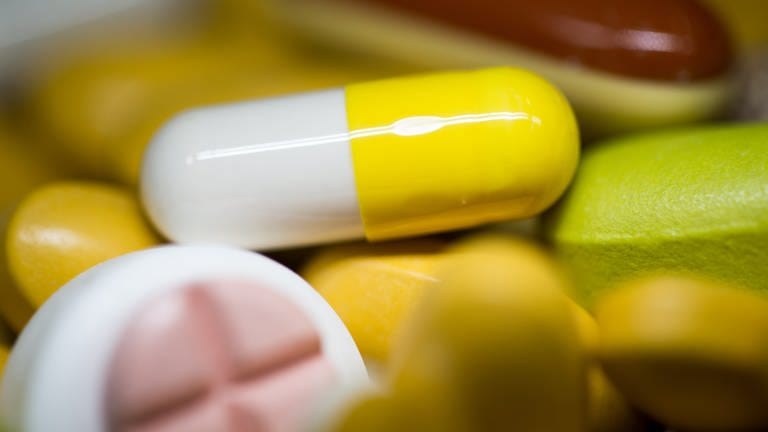 Tabletten, Kapseln und Pillen in verschiedenen Farben liegen in einem Medikamenten-Behälter einer Apotheke (Symbolbild).