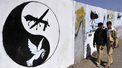Grafitti im Ying-Yang Stil mit den Abbildern einer Drohne und einer Friedenstaube anstelle des schwarzen und weißen Punkts im Symbol.  (Foto: IMAGO, IMAGO / Xinhua)