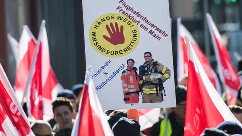 Ein Plakat "Hände weg! Wir sind Eure Rettung" wird 2018 von einem Mitglied der Flughafenfeuerwehr Frankfurt auf einer Demonstration gehalten (Foto: dpa Bildfunk, Andreas Arnold)