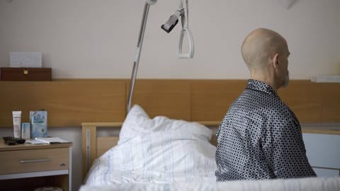 Mann sitzt seitlich abgewandt auf Krankenhausbett: Wenn keine Möglichkeit zur ambulanten Palliativversorgung vorhanden ist, bleibt nur das Sterben im Krankenhaus (Foto: IMAGO, imago/epd)