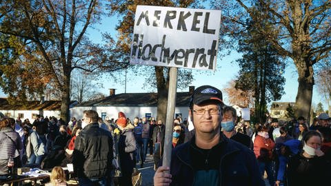 Demonstration gegen Corona-Maßnahmen des Querdenken-Bündnisses in Aichach, Bayern, im November 2020, ein Mann steht vereinzelt und trägt ein Schild mit der Aufschrift: "Merkel Hochverrat" (Foto: IMAGO, imageBROKER/Florian Bachmeier via www.imago-images.de)