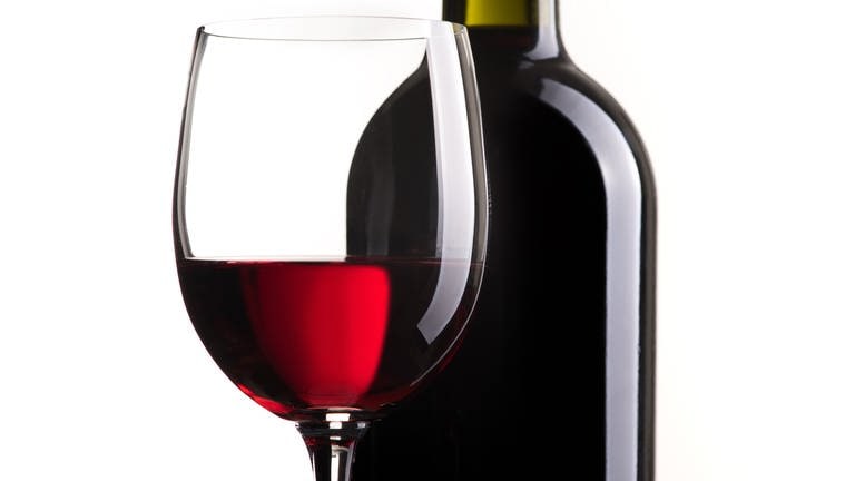 Rotweinglas und Flasche vor weißem Hintergrund (Foto: IMAGO, stokkete via www.imago-images.de)
