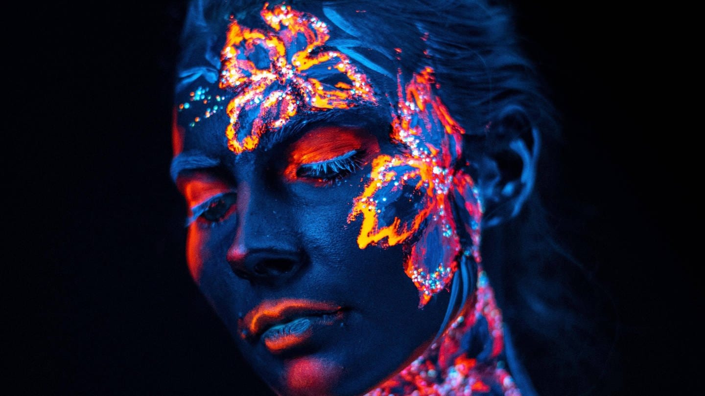 Bemaltes Gesicht einer Frau in UV-Licht (Foto: IMAGO, IMAGO / Panthermedia)