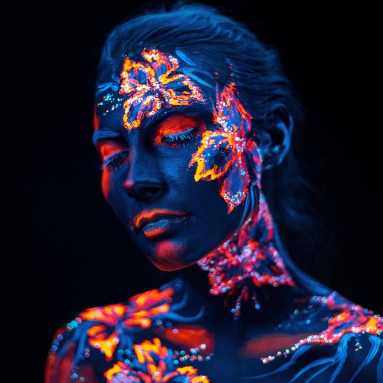Bemaltes Gesicht einer Frau in UV-Licht (Foto: IMAGO, IMAGO / Panthermedia)